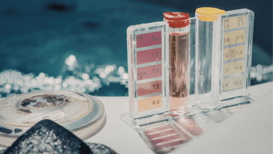 Pool water testing chemicals set by pool.